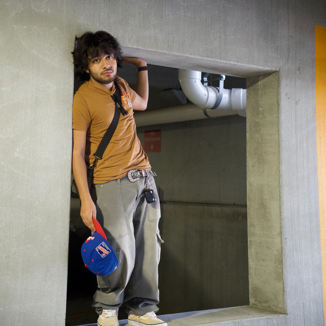 Kalashi standing in a concrete doorway, holding a baseball cap